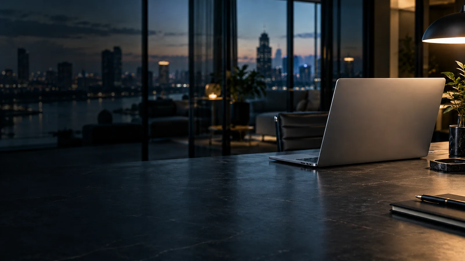 Laptop on a dark desk overlooking a softly lit city
